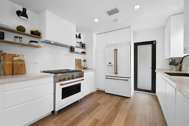 1060 NE 95th St, Miami Shores, FL 33138 - kitchen with high quality appliances, open shelves, light countertops, light wood-style floors, and white cabinets