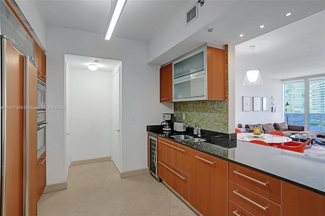 400 Alton Rd Unit 1409, Miami Beach, FL 33139 - kitchen featuring a sink, beverage cooler, backsplash, glass insert cabinets, and dark stone counters