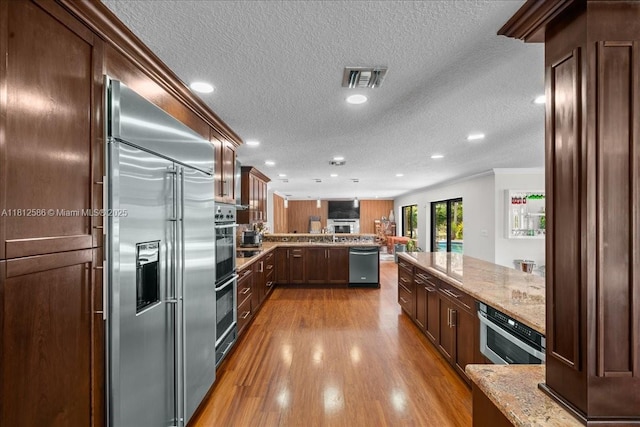 3030 SW 117th Ave, Davie, FL 33330 - kitchen with stainless steel appliances, a peninsula, ornamental molding, a textured ceiling, and wood finished floors