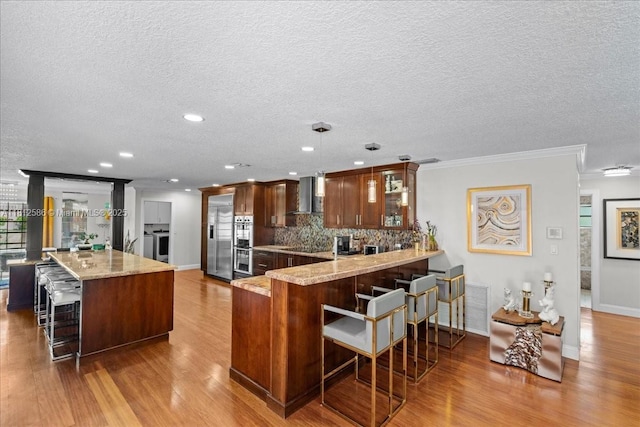 3030 SW 117th Ave, Davie, FL 33330 - kitchen featuring a breakfast bar, appliances with stainless steel finishes, crown molding, wood finished floors, and a peninsula