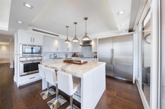 2901 S Bayshore Dr Unit 17G/H, Miami, FL 33133 - kitchen featuring built in appliances, dark wood-style flooring, tasteful backsplash, light stone counters, and a center island