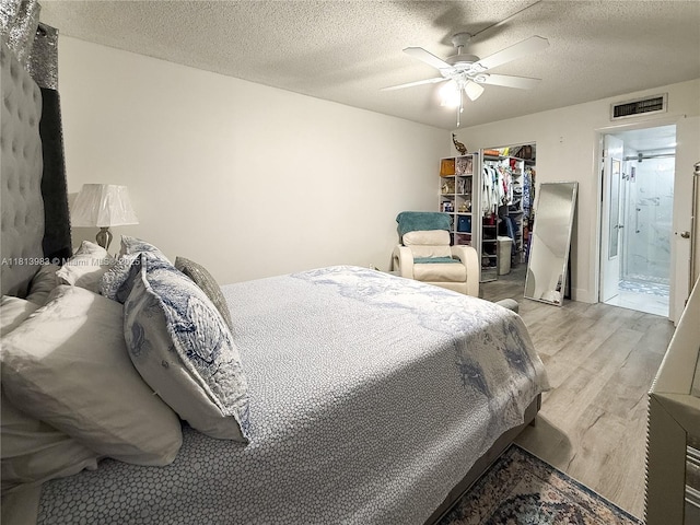 700 Lori Dr Unit 201, Palm Springs, FL 33461 - bedroom featuring light wood finished floors, a walk in closet, a closet, a textured ceiling, and a ceiling fan