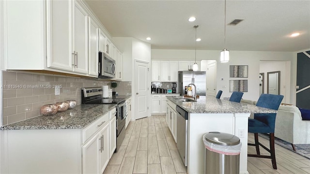486 Disa Dr, Davenport, FL 33837 - kitchen featuring appliances with stainless steel finishes, a breakfast bar area, a sink, wood finish floors, and recessed lighting