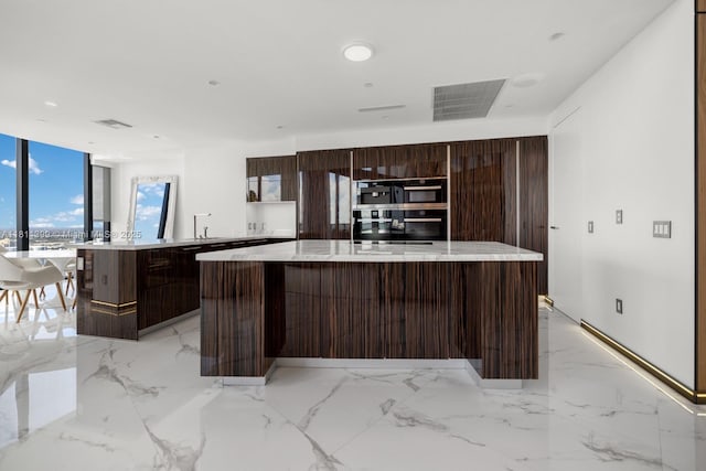18555 Collins Ave Unit 4603, Sunny Isles Beach, FL 33160 - kitchen with modern cabinets, a spacious island, dark brown cabinets, and light marble finish flooring
