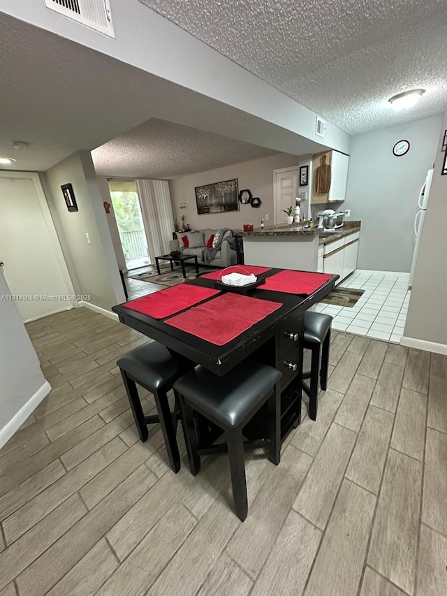 3995 W Mcnab Rd Unit B212, Pompano Beach, FL 33069 - dining room featuring wood finish floors, a textured ceiling, and baseboards