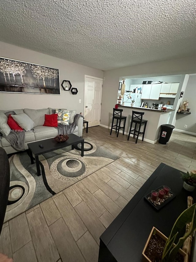 3995 W Mcnab Rd Unit B212, Pompano Beach, FL 33069 - living room featuring wood finish floors, a textured ceiling, and baseboards