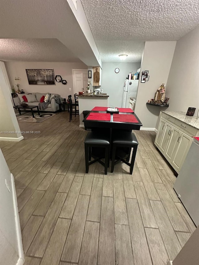 3995 W Mcnab Rd Unit B212, Pompano Beach, FL 33069 - dining area featuring a textured ceiling, light wood finished floors, and baseboards