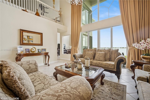 tiled living room featuring a high ceiling, healthy amount of natural light, a chandelier, and baseboards