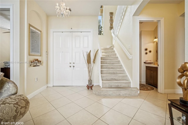foyer entrance featuring stairway, light tile patterned floors, a chandelier, and baseboards