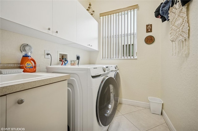 laundry area featuring separate washer and dryer, cabinet space, baseboards, and light tile patterned floors