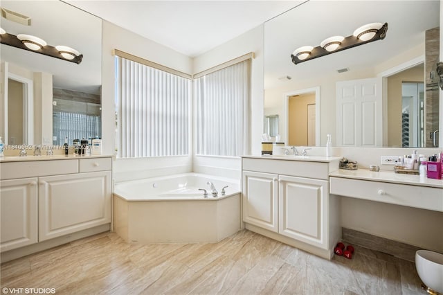 full bath with a garden tub, two vanities, and a stall shower