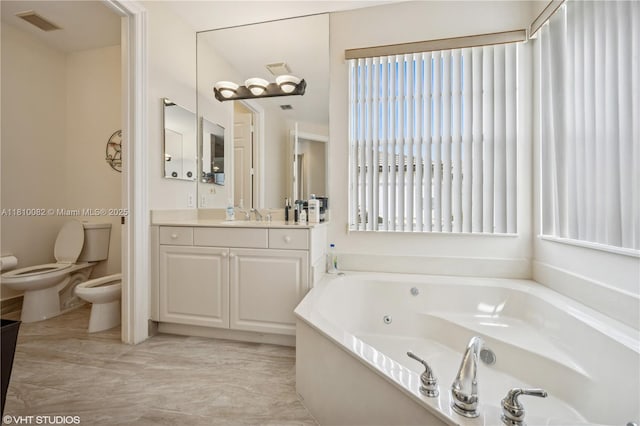 full bath featuring vanity, a tub with jets, toilet, and a bidet