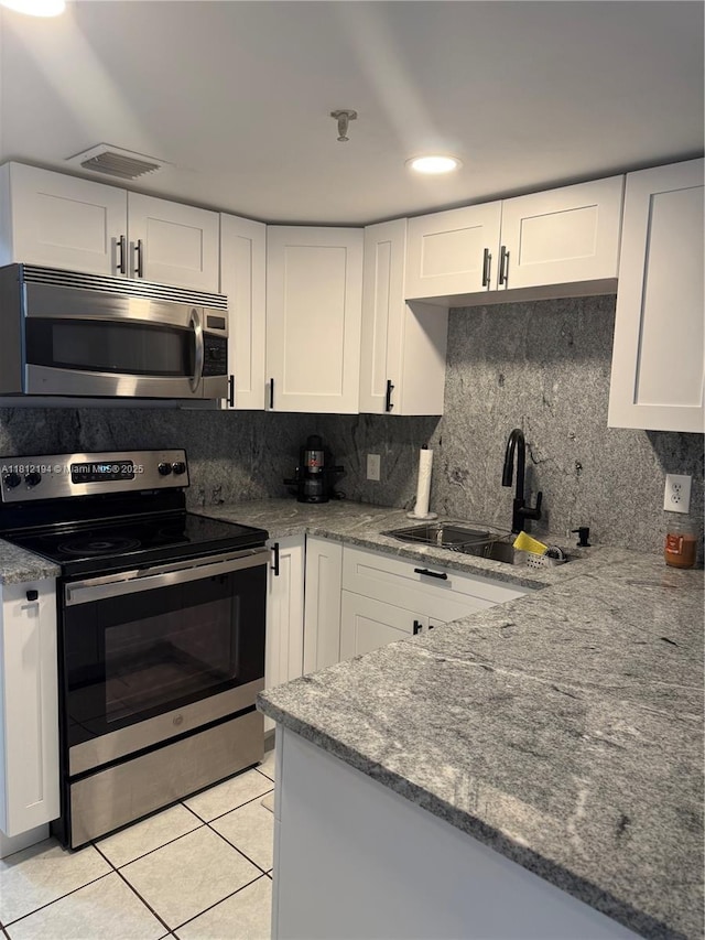 10661 SW 108th Ave Unit 2E, Miami, FL 33176 - kitchen featuring appliances with stainless steel finishes, light tile patterned floors, white cabinets, stone counters, and recessed lighting
