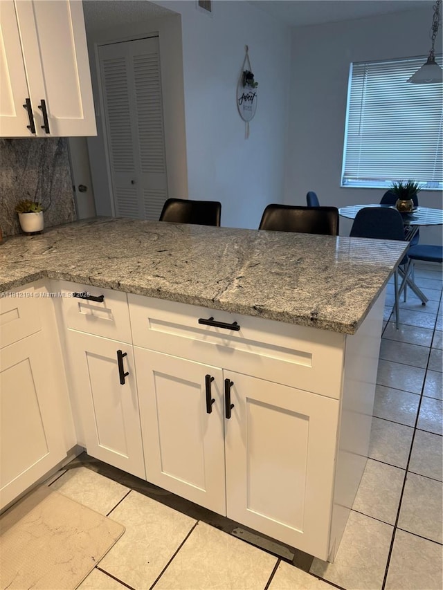 10661 SW 108th Ave Unit 2E, Miami, FL 33176 - kitchen with light tile patterned flooring, white cabinetry, a peninsula, and light stone counters