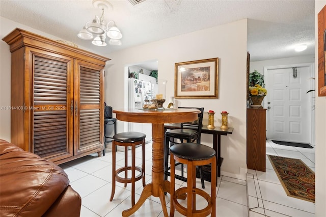 4119 NE 21st Ter, Lighthouse Point, FL 33064 - dining space featuring a chandelier, a textured ceiling, light tile patterned floors, and baseboards