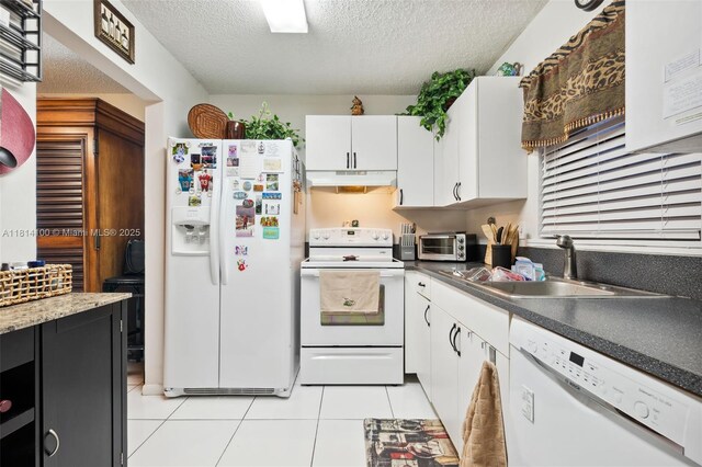 4119 NE 21st Ter, Lighthouse Point, FL 33064 - kitchen with white appliances, under cabinet range hood, light tile patterned floors, white cabinetry, and a textured ceiling
