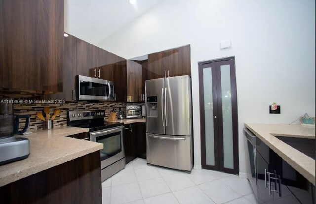 1353 Majesty Ter, Weston, FL 33327 - kitchen with stainless steel appliances, backsplash, light countertops, dark brown cabinetry, and light tile patterned flooring
