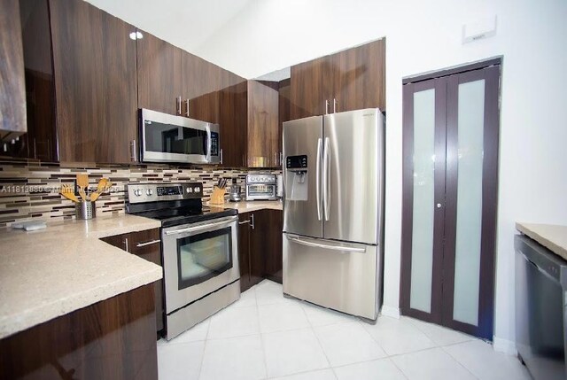 1353 Majesty Ter, Weston, FL 33327 - kitchen featuring stainless steel appliances, light countertops, tasteful backsplash, dark brown cabinetry, and light tile patterned floors