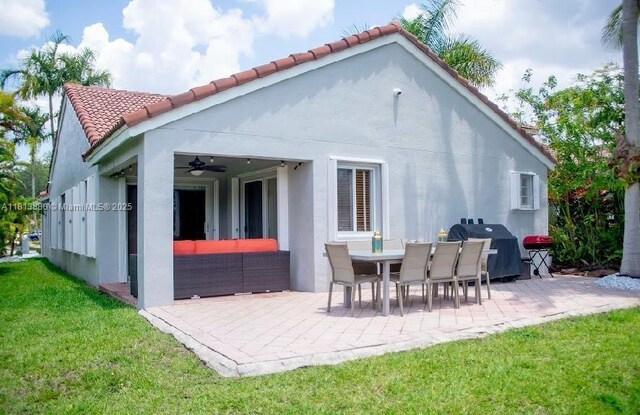 1353 Majesty Ter, Weston, FL 33327 - rear view of house with a patio area, a ceiling fan, a tile roof, a yard, and stucco siding