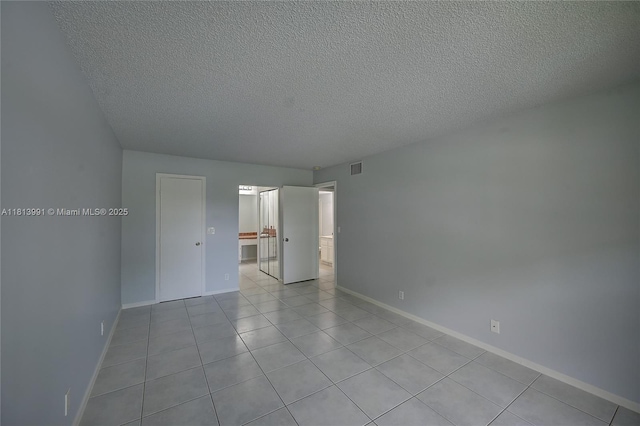 9965 Pineapple Tree Dr Unit 203, Boynton Beach, FL 33436 - unfurnished bedroom with a textured ceiling, light tile patterned flooring, and ensuite bath