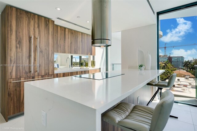 9901 W Bay Harbor Dr Unit 601, Bay Harbor Islands, FL 33154 - kitchen featuring modern cabinets, brown cabinetry, black electric stovetop, light tile patterned floors, and exhaust hood
