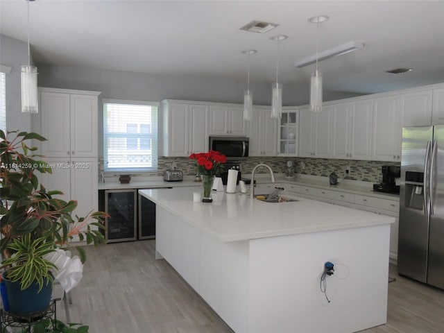 16815 SW 49th Ct, Miramar, FL 33027 - kitchen with stainless steel appliances, a sink, beverage cooler, tasteful backsplash, and light wood finished floors
