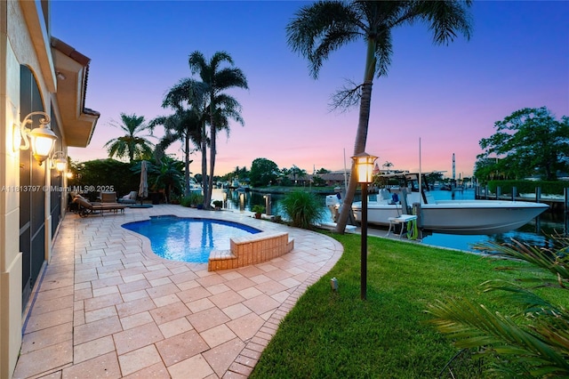 1437 SE 13th St, Deerfield Beach, FL 33441 - pool at dusk with boat lift, a patio area, a boat dock, an outdoor pool, and a yard