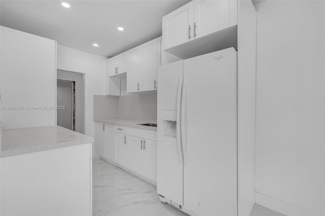 1246 Sharazad Blvd, Opa-Locka, FL 33054 - kitchen with white fridge with ice dispenser, light marble finish flooring, recessed lighting, white cabinetry, and light countertops