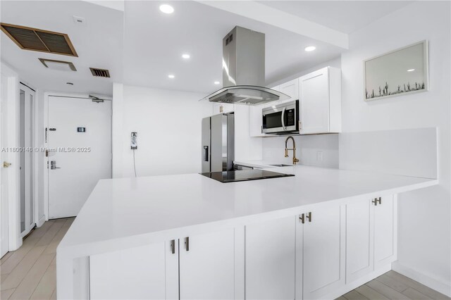 20379 W Country Club Dr Unit 1237, Aventura, FL 33180 - kitchen featuring island exhaust hood, stainless steel appliances, a peninsula, light countertops, and light wood-type flooring