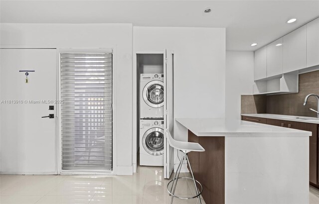 2715 Tigertail Ave Unit 102, Miami, FL 33133 - laundry room featuring stacked washer / drying machine, light tile patterned flooring, and recessed lighting