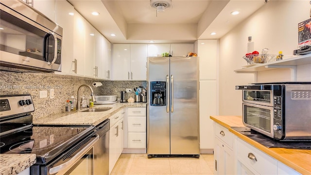 20355 NE 34th Ct Unit 325, Aventura, FL 33180 - kitchen with stainless steel appliances, a sink, white cabinetry, light tile patterned floors, and decorative backsplash