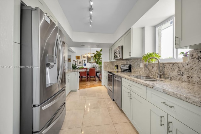 2825 Granada Blvd Unit 3B, Coral Gables, FL 33134 - kitchen featuring appliances with stainless steel finishes, backsplash, light stone counters, light tile patterned floors, and white cabinets
