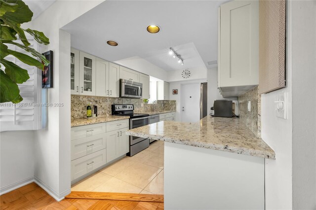 2825 Granada Blvd Unit 3B, Coral Gables, FL 33134 - kitchen with appliances with stainless steel finishes, decorative backsplash, glass insert cabinets, light stone counters, and white cabinetry