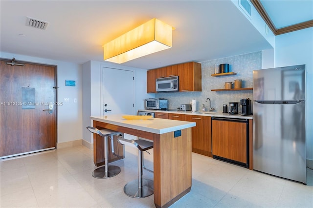 6801 Collins Ave Unit 510Door 512, Miami Beach, FL 33141 - kitchen with stainless steel appliances, brown cabinetry, light countertops, decorative backsplash, and a breakfast bar area