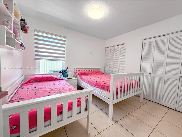 14751 SW 158th St, Miami, FL 33187 - bedroom with light tile patterned floors, two closets, and a textured ceiling