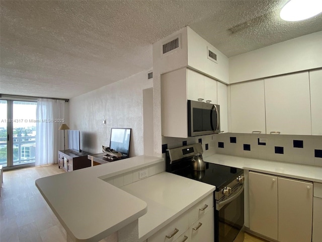 1500 Bay Rd Unit 1274S, Miami Beach, FL 33139 - kitchen featuring stainless steel appliances, a textured ceiling, light countertops, white cabinets, and a peninsula