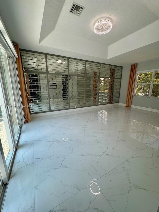 4248 SW 185th Ave, Miramar, FL 33029 - empty room with a tray ceiling, marble finish floors, a textured ceiling, and baseboards
