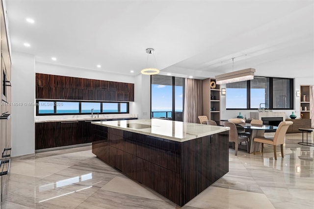 18555 Collins Ave Unit 2105, Sunny Isles Beach, FL 33160 - kitchen featuring modern cabinets, a sink, a center island, dark brown cabinetry, and light marble finish floors