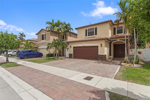 3502 W 86th Ter, Hialeah, FL 33018 - mediterranean / spanish-style house with an attached garage, stone siding, stucco siding, decorative driveway, and a tiled roof