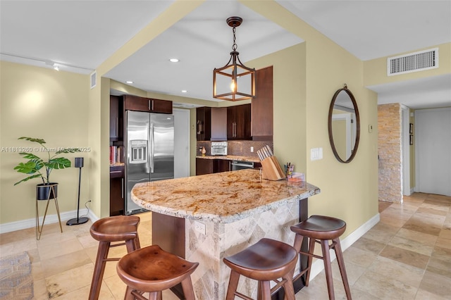 875 E Camino Real Unit 5D, Boca Raton, FL 33432 - kitchen featuring stainless steel appliances, a breakfast bar area, a peninsula, baseboards, and decorative light fixtures