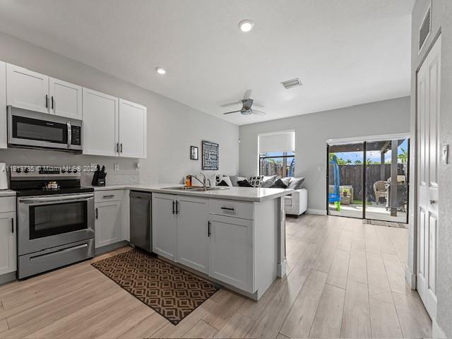 18058 SW 147th Ct, Miami, FL 33187 - kitchen featuring stainless steel appliances, a peninsula, light wood-style floors, a ceiling fan, and recessed lighting