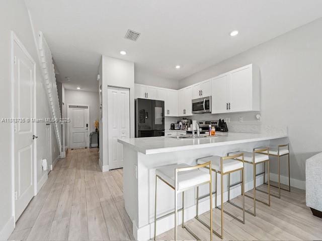 18058 SW 147th Ct, Miami, FL 33187 - kitchen with stainless steel microwave, fridge, a peninsula, white cabinets, and light countertops