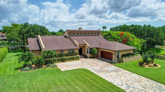 13241 SW 32nd Ct, Davie, FL 33330 - view of front of home with stucco siding, an attached garage, a front yard, decorative driveway, and a chimney