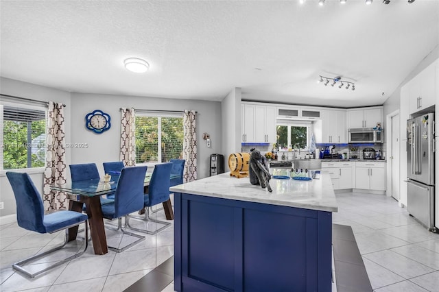 15240 SW 188th St, Miami, FL 33187 - kitchen with stainless steel appliances, plenty of natural light, light tile patterned flooring, white cabinetry, and a textured ceiling
