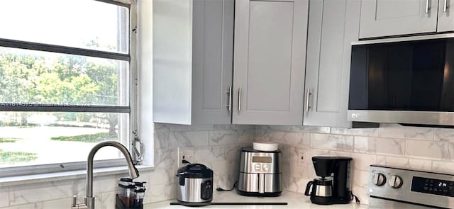 5300 Washington St Unit T227, Hollywood, FL 33021 - kitchen with stainless steel microwave, backsplash, light countertops, and white cabinetry