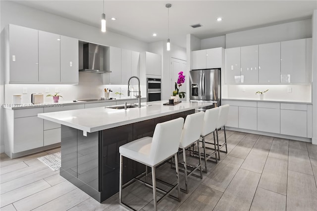 4381 SW 178th Ave, Miramar, FL 33029 - kitchen featuring wall chimney range hood, a sink, stainless steel appliances, light countertops, and a kitchen breakfast bar