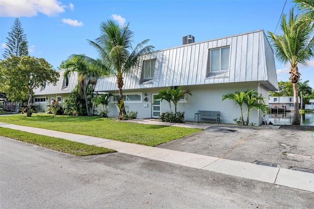 1370 NE 40th Dr, Oakland Park, FL 33334 - view of front of property with a front yard, stucco siding, and a metal roof