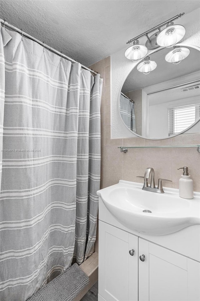1370 NE 40th Dr, Oakland Park, FL 33334 - bathroom featuring a textured ceiling, tile walls, vanity, wood finished floors, and a shower with shower curtain