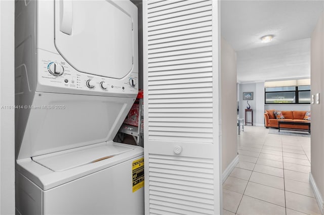 5845 Collins Ave Unit 501, Miami Beach, FL 33140 - laundry room featuring stacked washing machine and dryer, light tile patterned flooring, and baseboards
