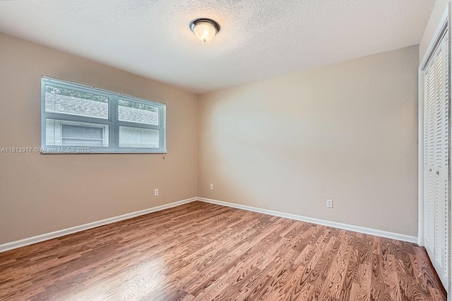 9802 N Military Trl, Palm Beach Gardens, FL 33410 - unfurnished bedroom with a closet, wood finished floors, baseboards, and a textured ceiling